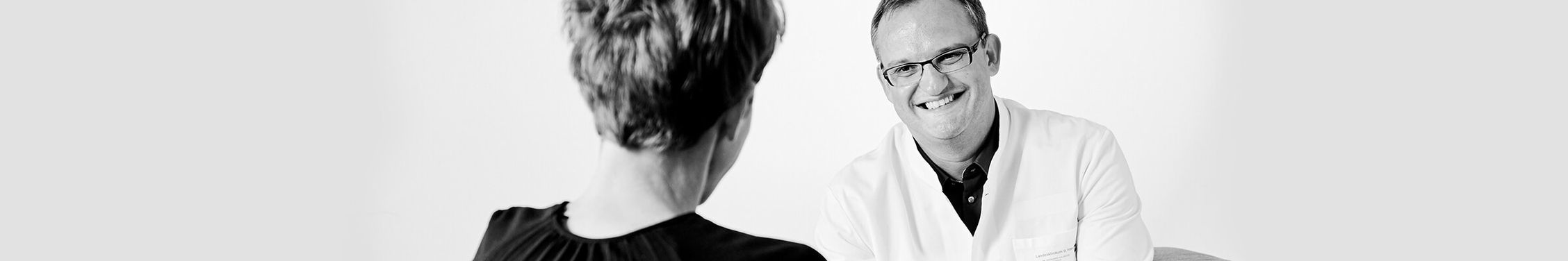 Ein Doktor und eine Frau sitzen sich gegenüber für ein Beratungsgespräch
