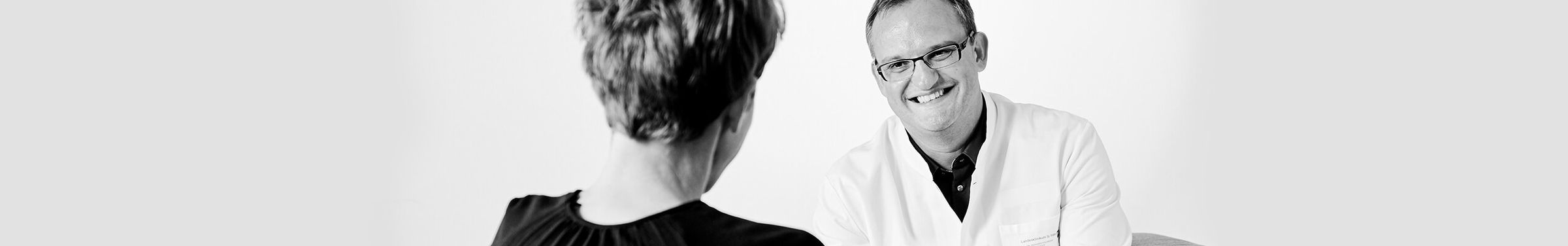 Ein Doktor und eine Frau sitzen sich gegenüber für ein Beratungsgespräch